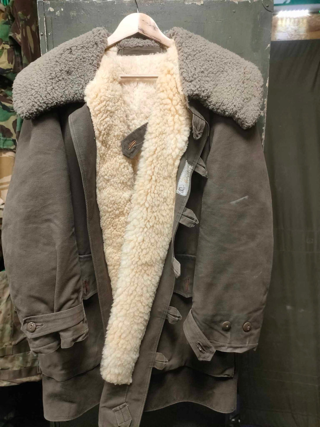 Army green parka with large green sheepskin collar and white sheepskin fleece lining with loop button fastening